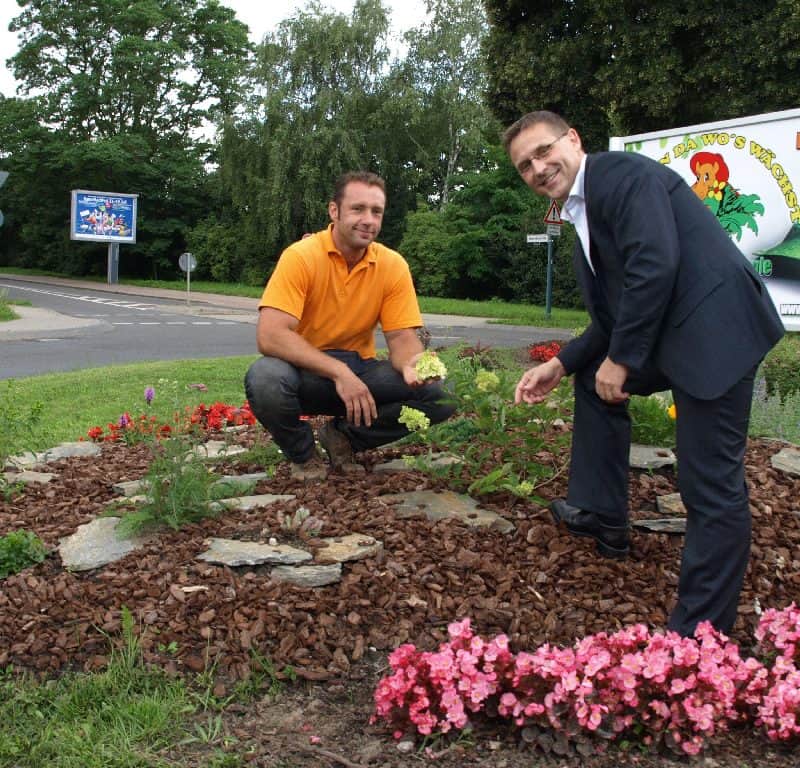 Schön bunt: Beigeordneter Markus Derling (rechts) bewundert die Arbeit der Gärtnerei von Andreas Irrling. Diese hat für drei Jahre ehrenamtlich die Pflege des Kreisels in der Nuhnenstraße übernommen. © Foto: MOZ/Andrea Weil